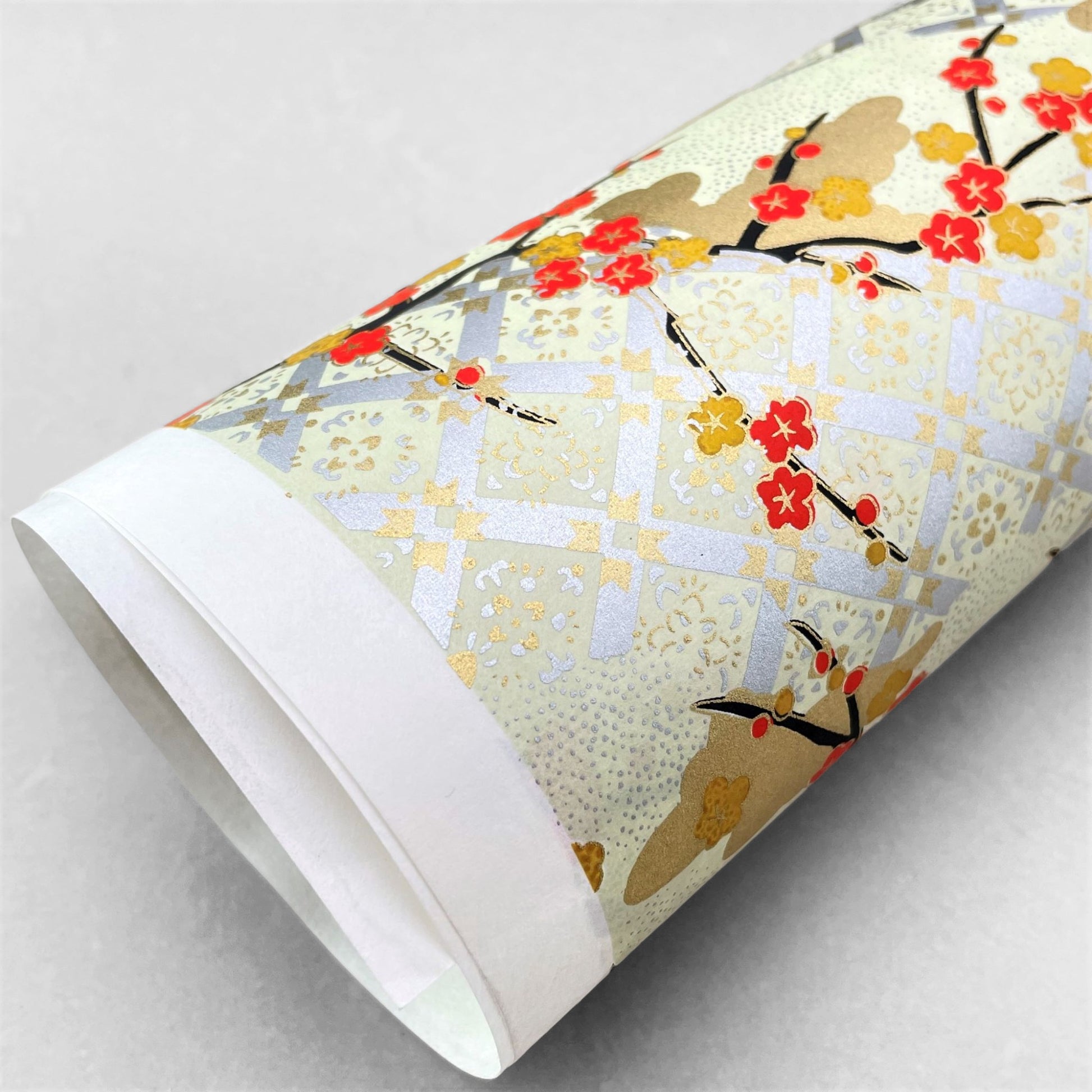 japanese silk-screen handmade paper, chiyogami, showing branches of red cherry blossom and gold clouds on a backdrop of silver, cream and gold