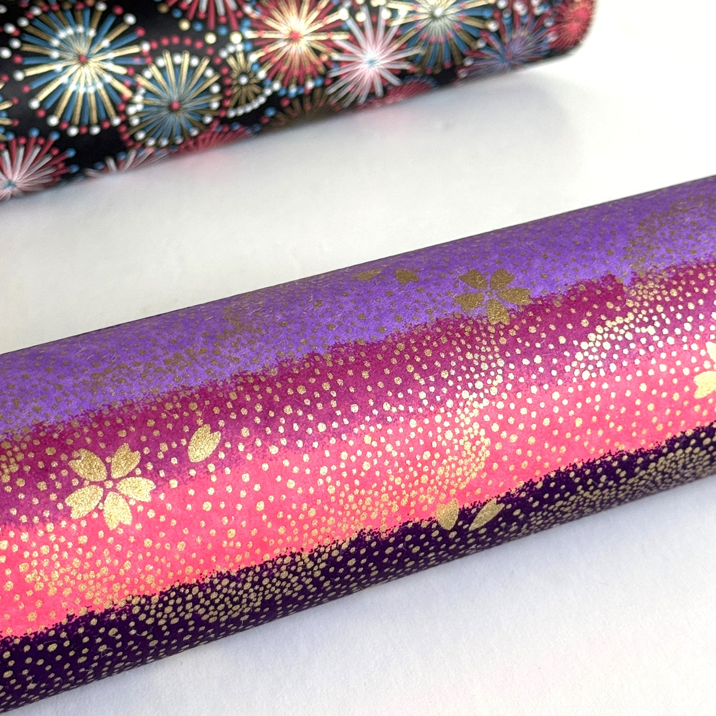 japanese chiyogami paper in stripes of pink, lilac and purple with gold clouds and flowers. Rolled