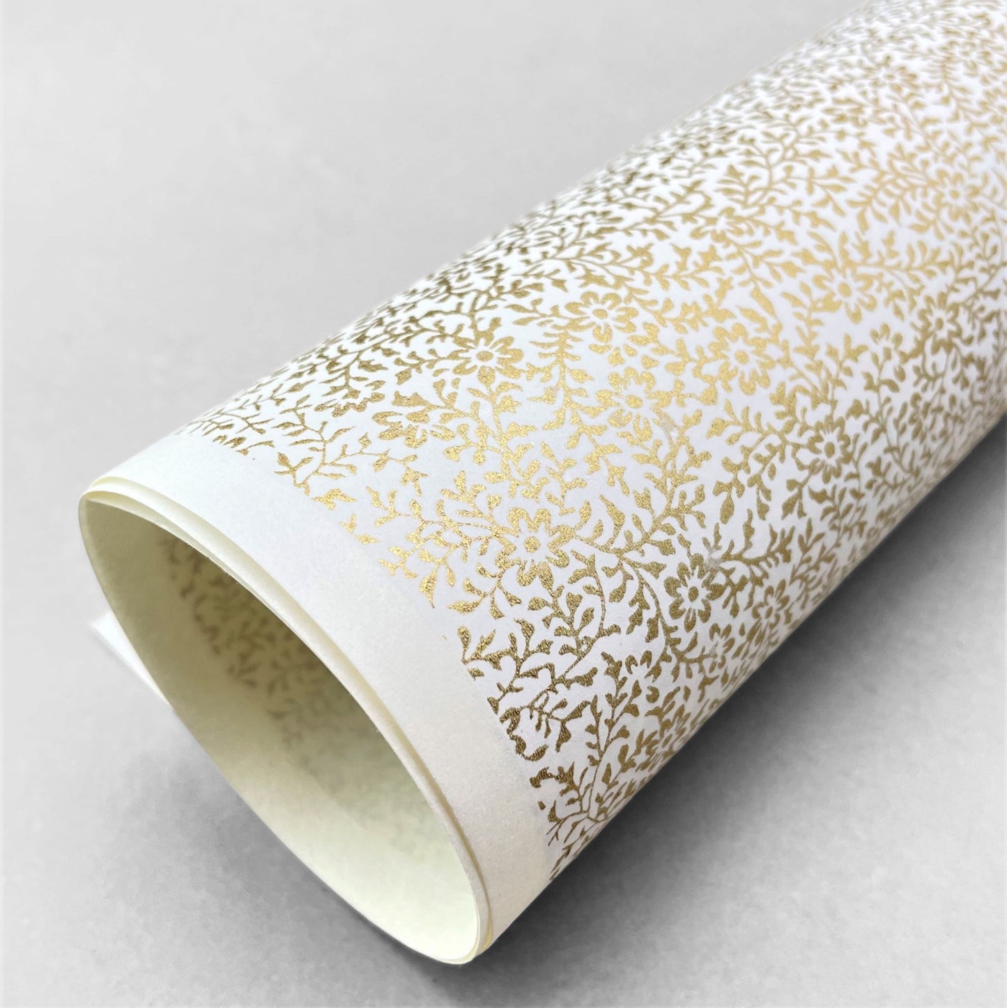 japanese silk-screen handmade paper showing a dainty gold botanical repeat design on ivory backdrop