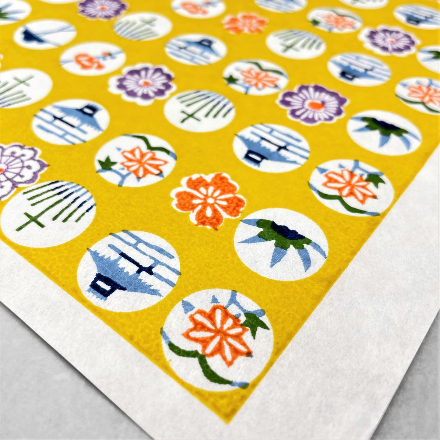 japanese silk-screen handmade paper showing circles of traditional motifs on yellow backdrop
