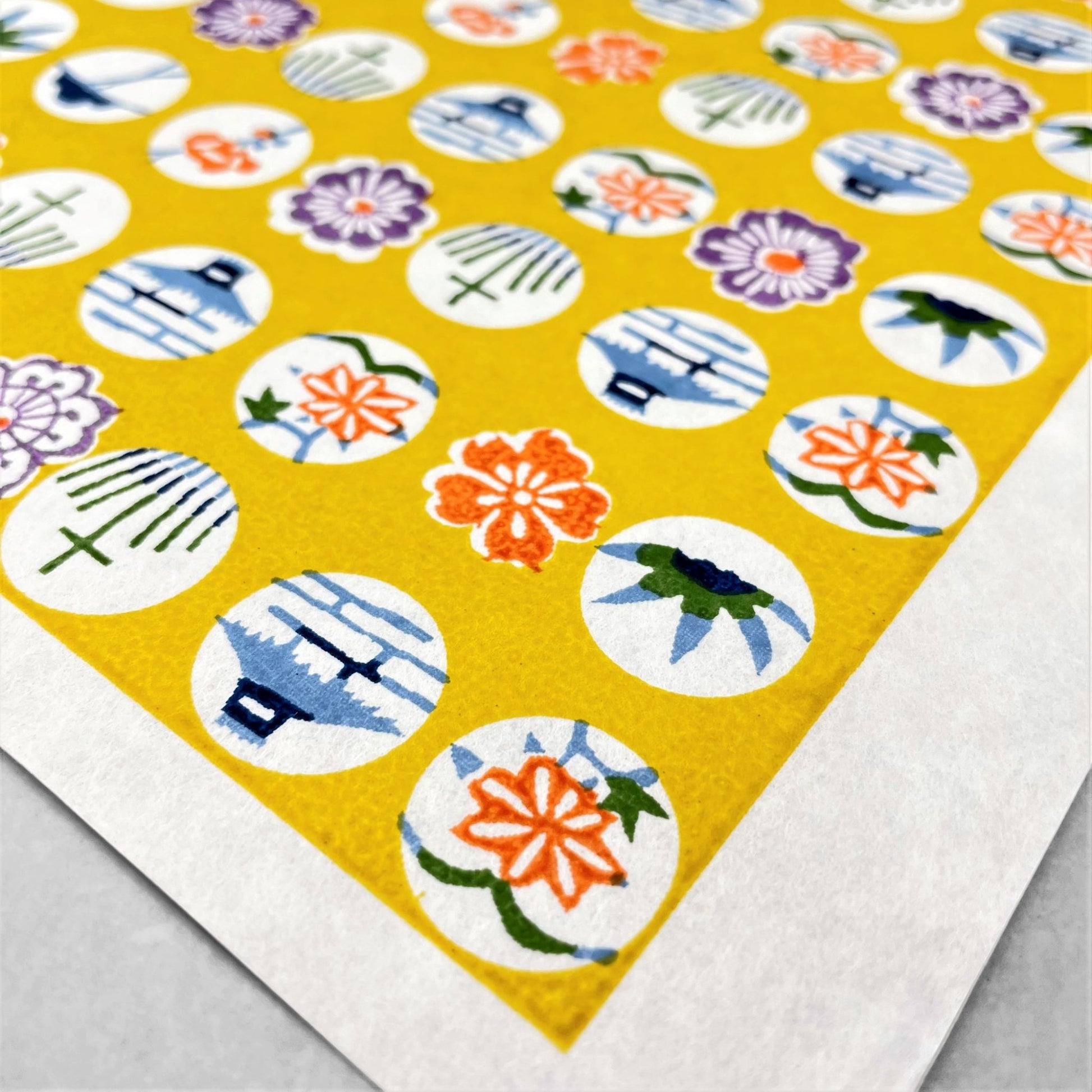 japanese silk-screen handmade paper showing circles of traditional motifs on yellow backdrop