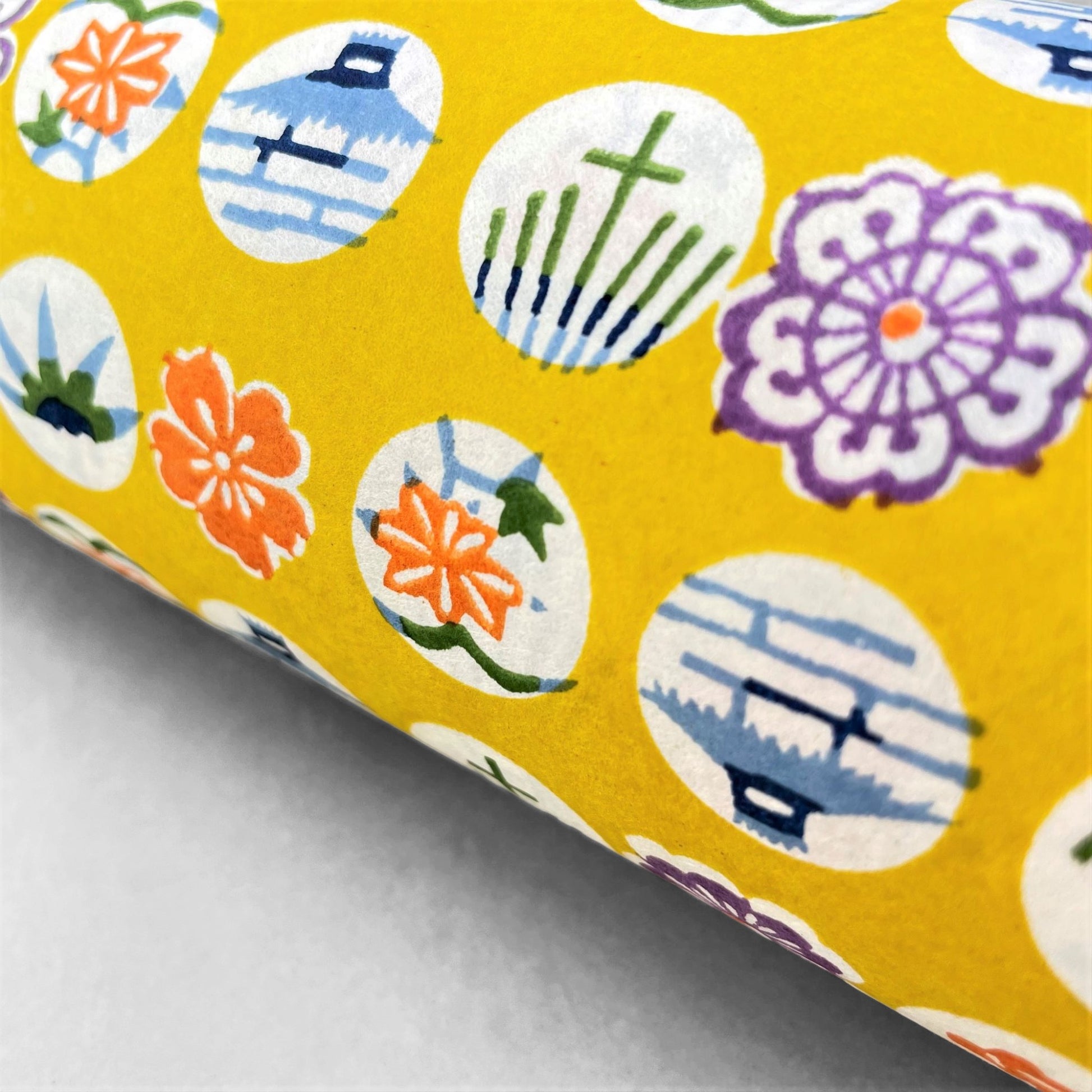 japanese silk-screen handmade paper showing circles of traditional motifs on yellow backdrop