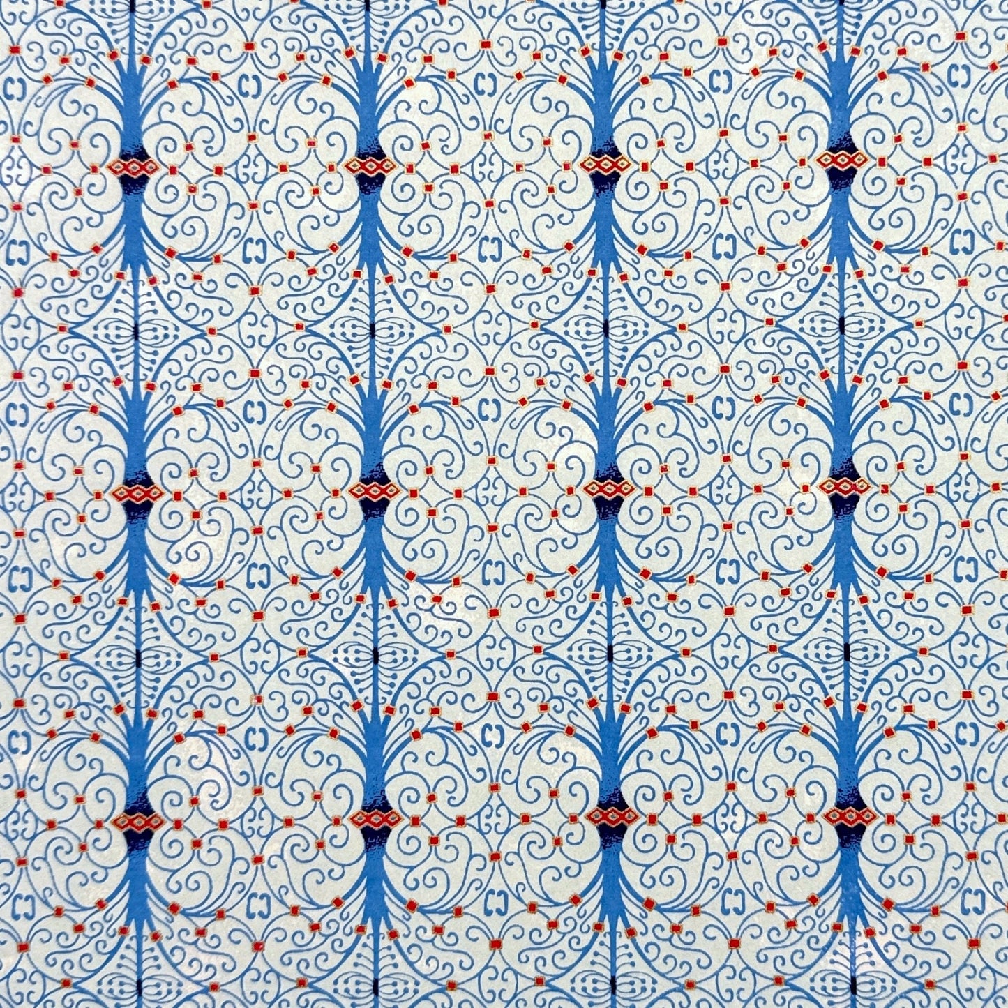 Japanese silkscreen chiyogami paper with a intricate filigree trellis design in blue with red and gold accent