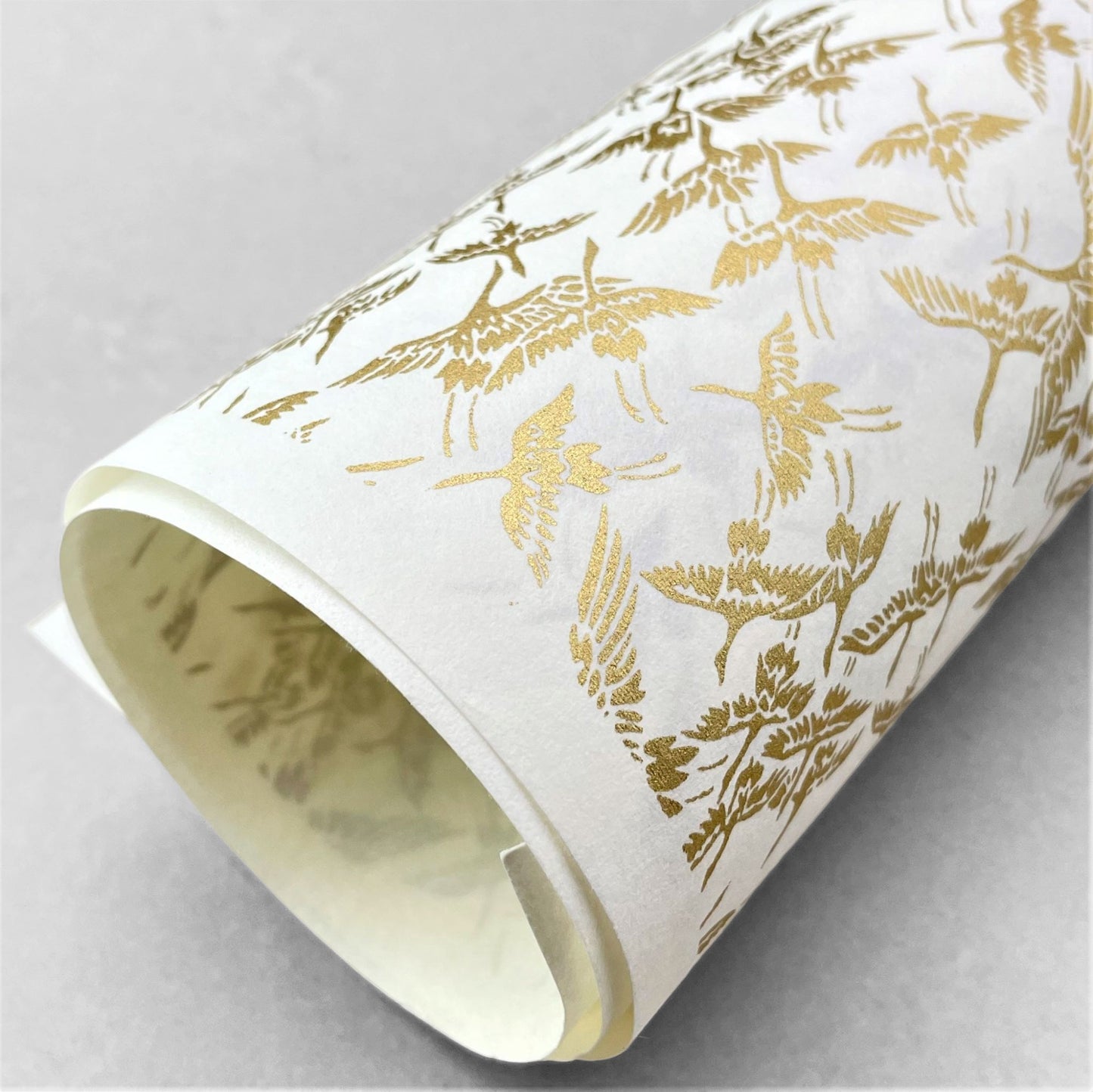 japanese silk-screen handmade paper showing gold cranes in flight on ivory backdrop