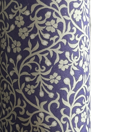 a sheet of Japanese silkscreen printed chiyogami paper with a small floral repeat pattern in grey and white on a periwinkle blue background. Close up