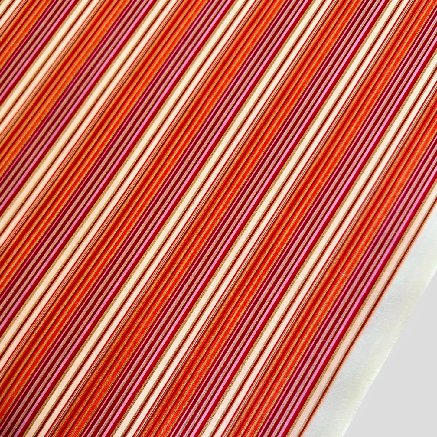 Japanese silkscreen chiyogami paper with a classic narrow stripe pattern in berry tones of red, pink, purple and gold.