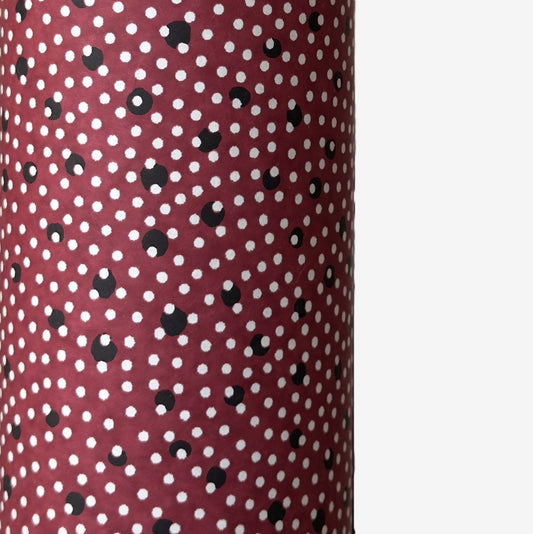 a sheet of Japanese chiyogami paper with an aubergine backdrop and a white dotted repeat arch pattern with black dots