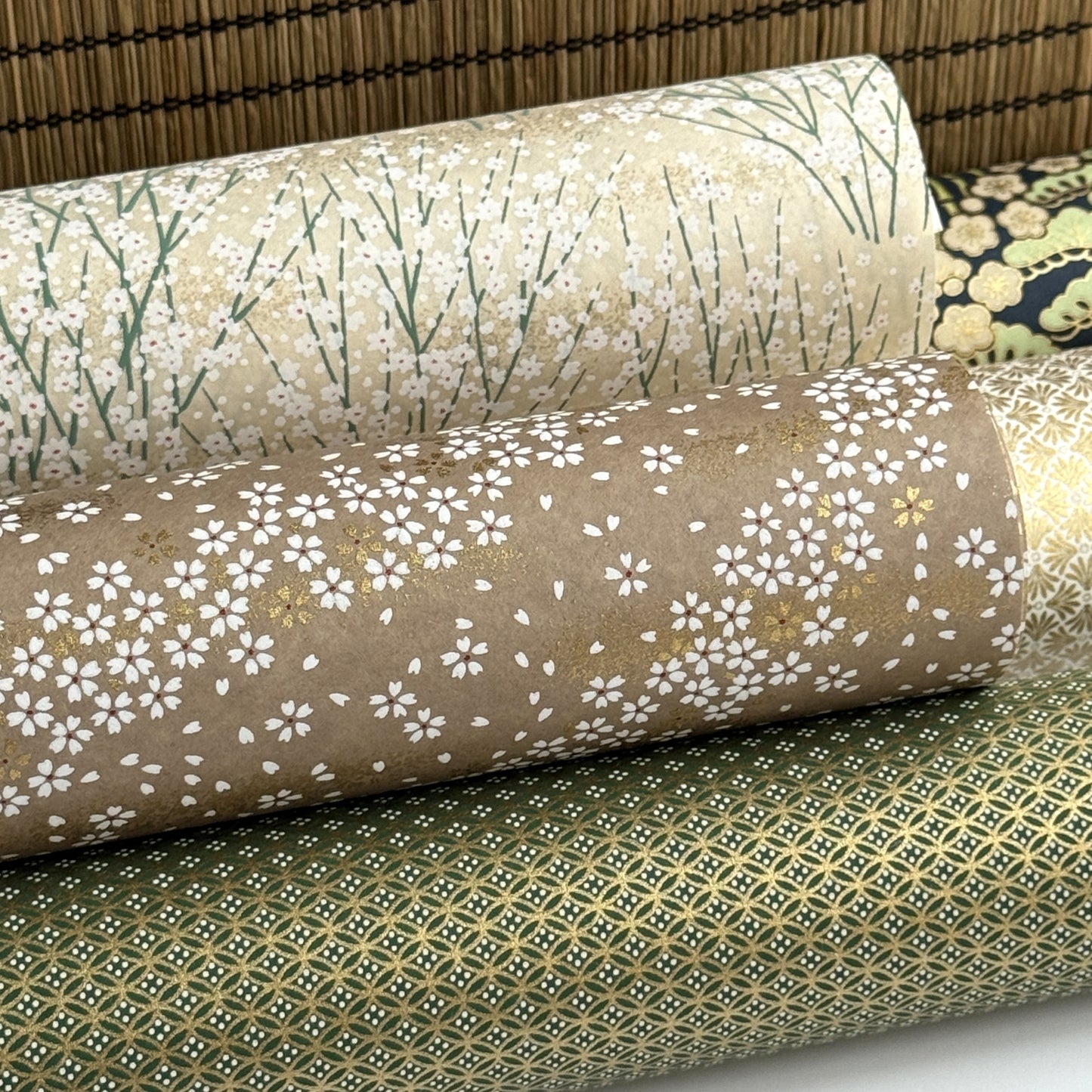 a sheet of Japanese silkscreen printed chiyogami paper with waves of tiny white and gold flowers on a soft taupe background with a dusting of gold.