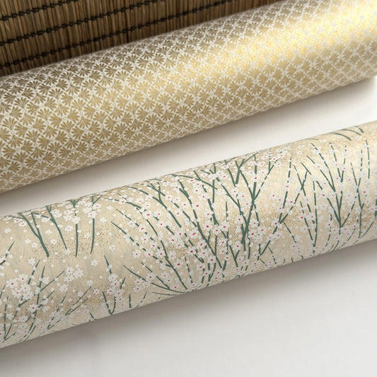 a sheet of Japanese silkscreen printed chiyogami paper with a delicate design of tufts of meadow grasses in flower in white, green on a cream background