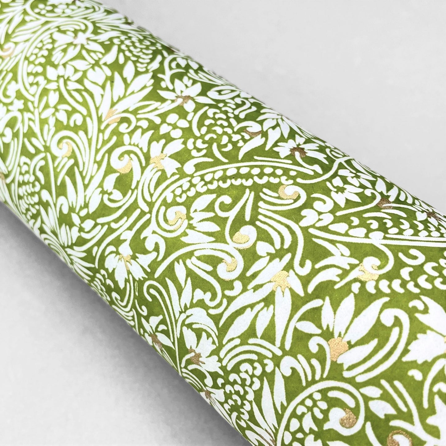 japanese silk-screen handmade paper showing green and white botanical repeat pattern with gold highlights