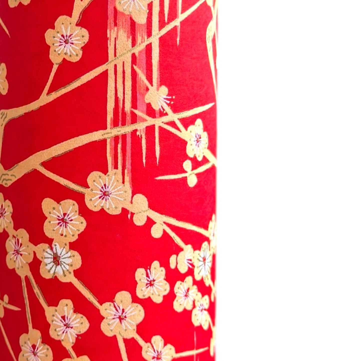 a sheet of Japanese silkscreen printed chiyogami paper with cream plum tree branches on red