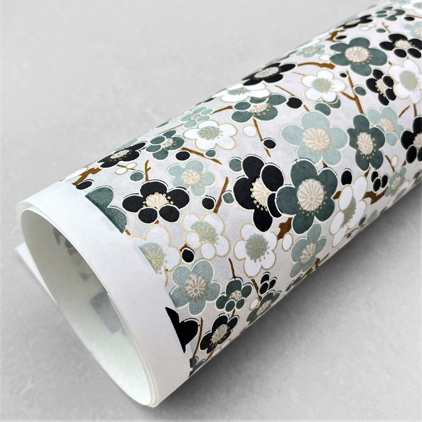 japanese silk-screen handmade paper showing soft green plum flower repeat pattern with gold highlights