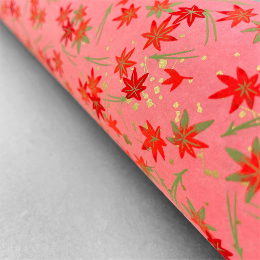 japanese silk-screen handmade paper showing pattern of red falling leaves on coral backdrop and gold highlights