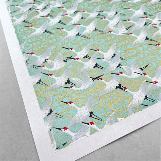 japanese silk-screen handmade paper showing white cranes in flight on a light teal and gold backdrop