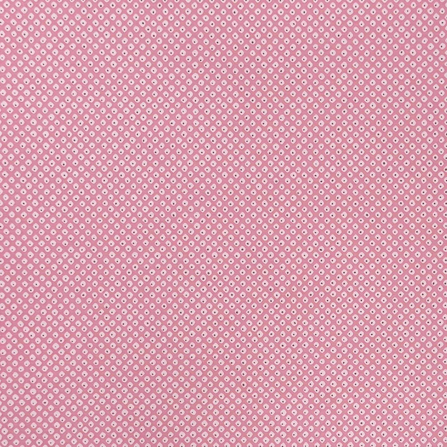 a sheet of chiyogami paper with a pink background and little irregular white dots with a gold center