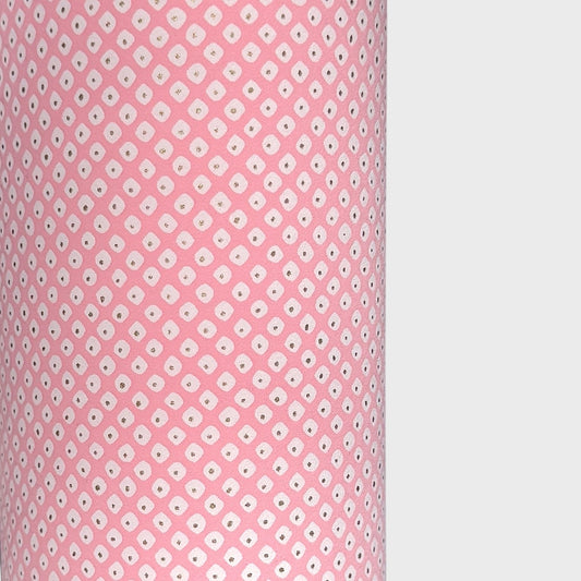 a sheet of chiyogami paper with a pink background and little irregular white dots with a gold center