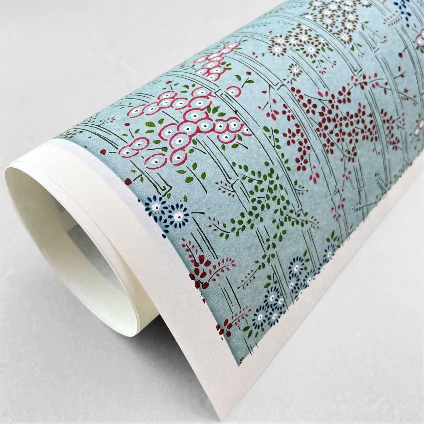 japanese silk-screen handmade paper showing pattern of bamboo, flowers and foliage on light teal backdrop