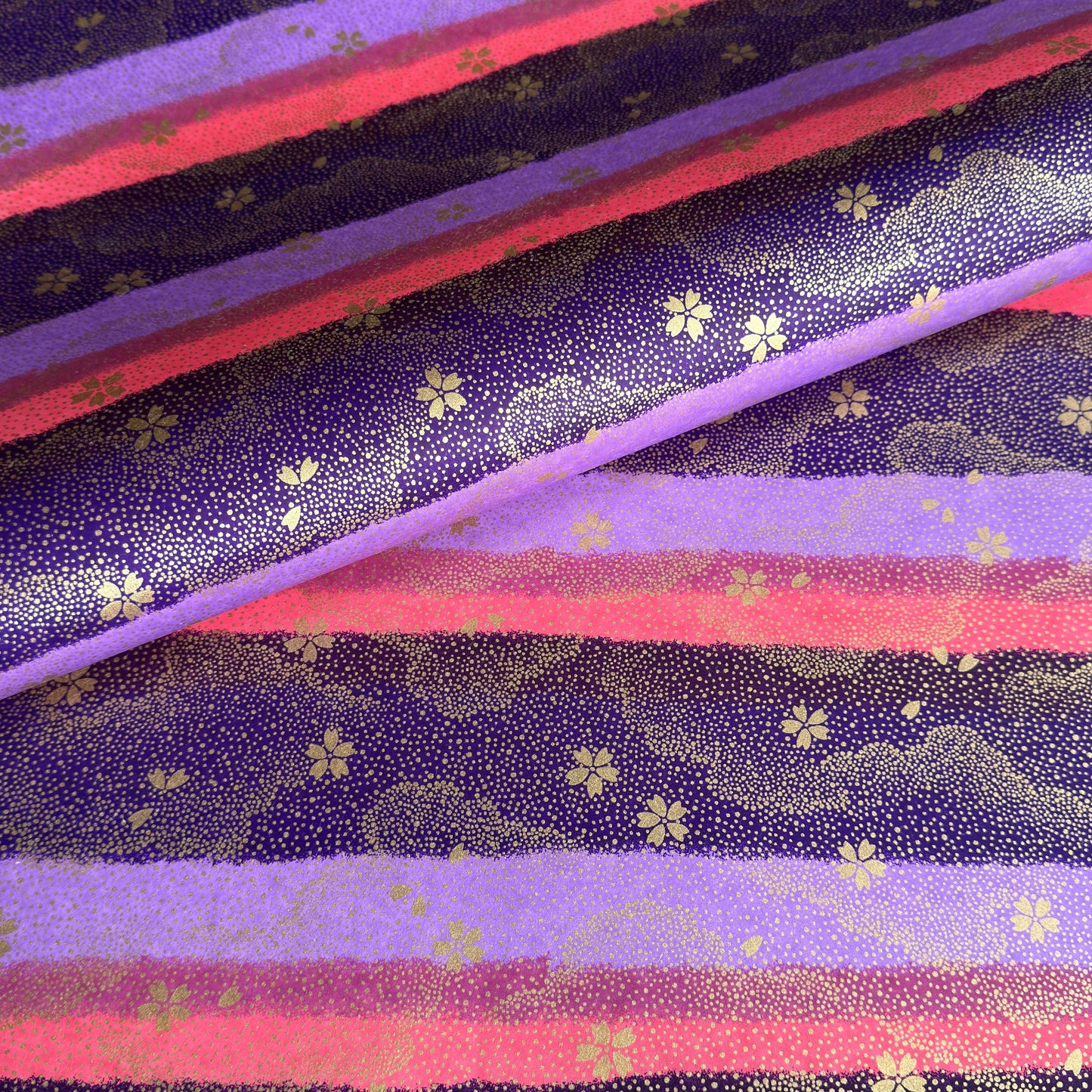 japanese chiyogami paper in stripes of pink, lilac and purple with gold clouds and flowers