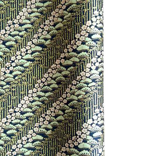 a sheet of Japanese silkscreen printed chiyogami paper with a design of trees, bamboo and plum blossom in a palette of mint green, white and dark indigo