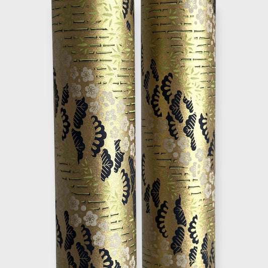 Japanese chiyogami paper with a design of trees, bamboo and plum blossom in indigo, green and white on a vintage gold backdrop. Rolled