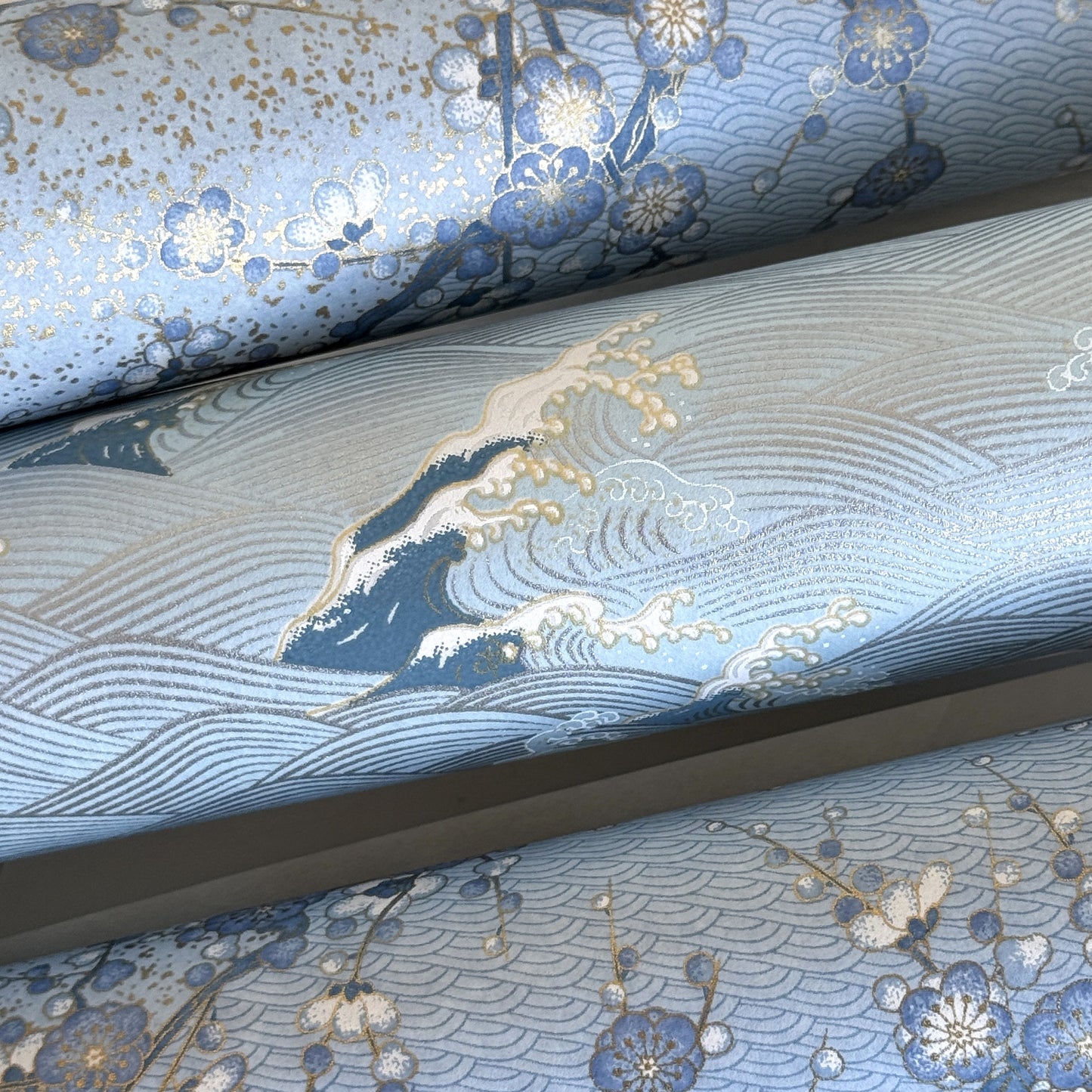 Japanese chiyogami paper with a wave pattern in pale blue, gold and silver. Close-up