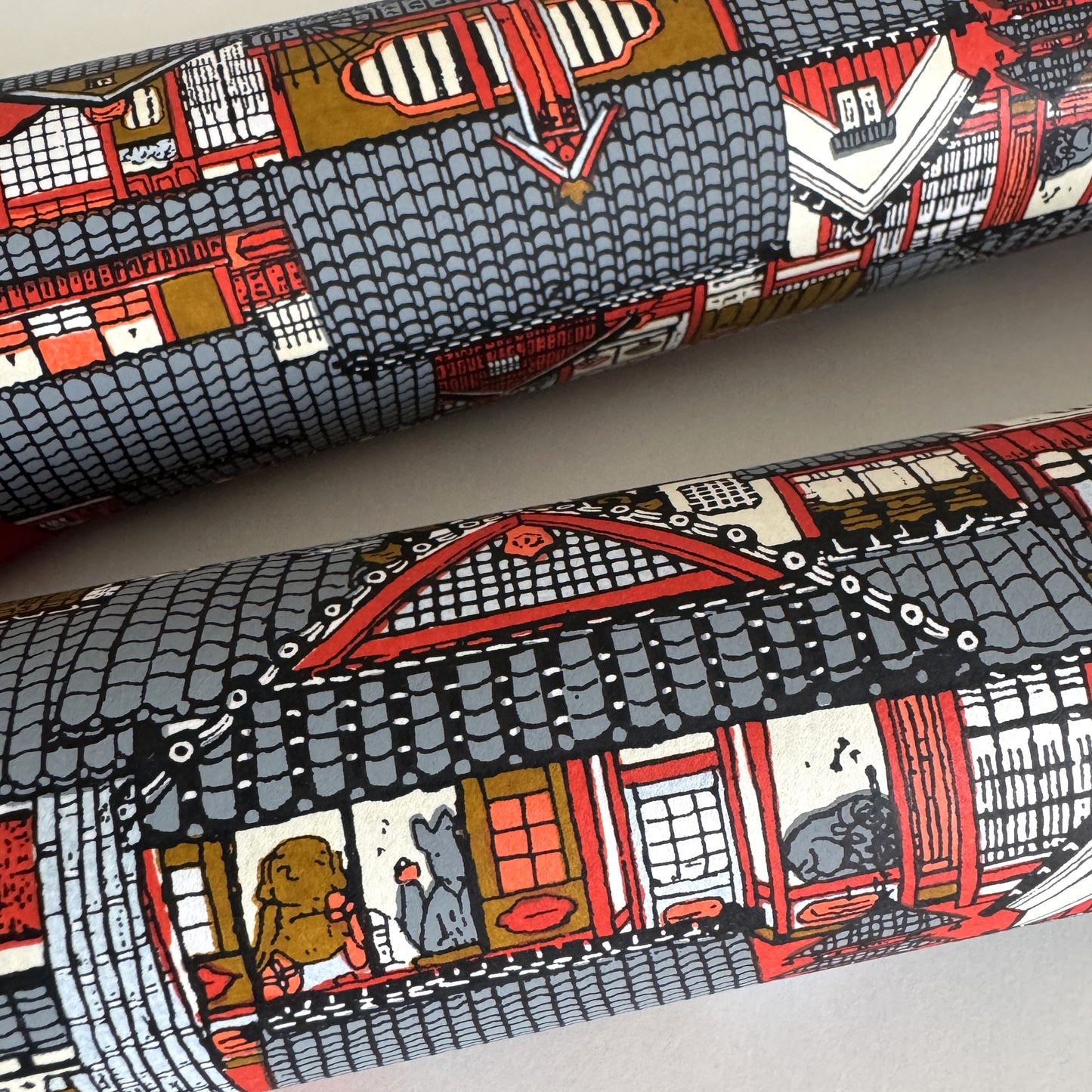 Japanese chiyogami paper (silkscreen printed) with a city landscape in grey, red and orange. Rolled & close-up