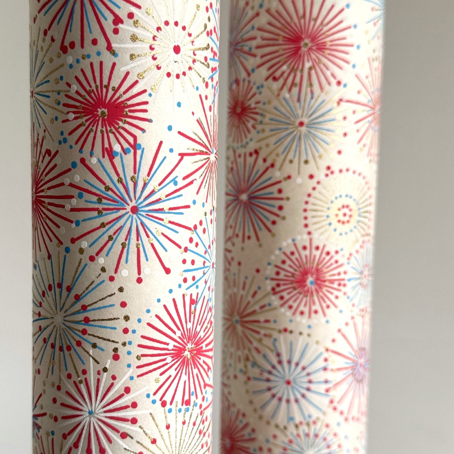japanese chiyogami silkscreen printed paper with a pattern of fireworks in reds, pinks and lilacs on an ivory background. Close-up