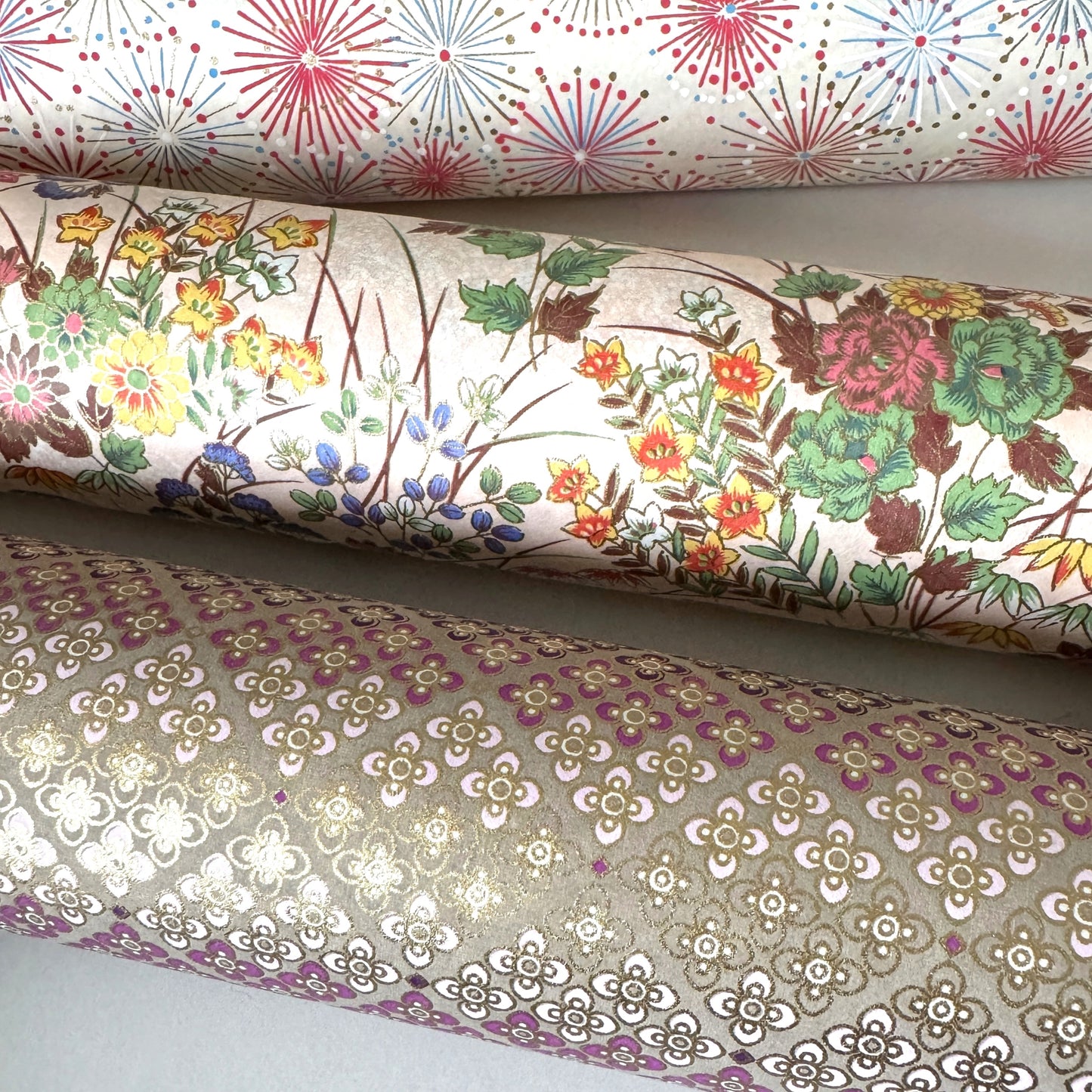 japanese silkscreen printed paper with a delicate floral bouquet design on blush pink background. Rolled alongside other papers