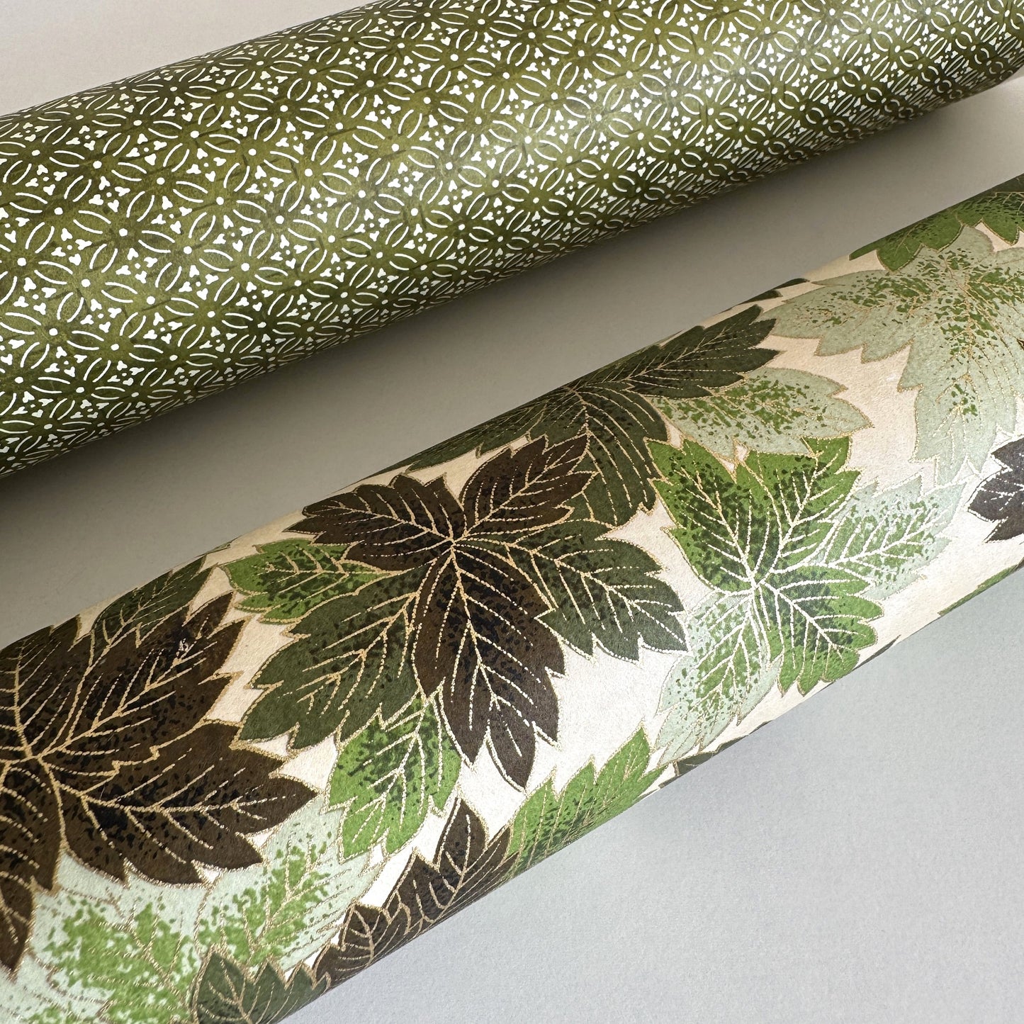 Japanese chiyogami paper with a pattern of green leaves in various tones with gold accent. Rolled