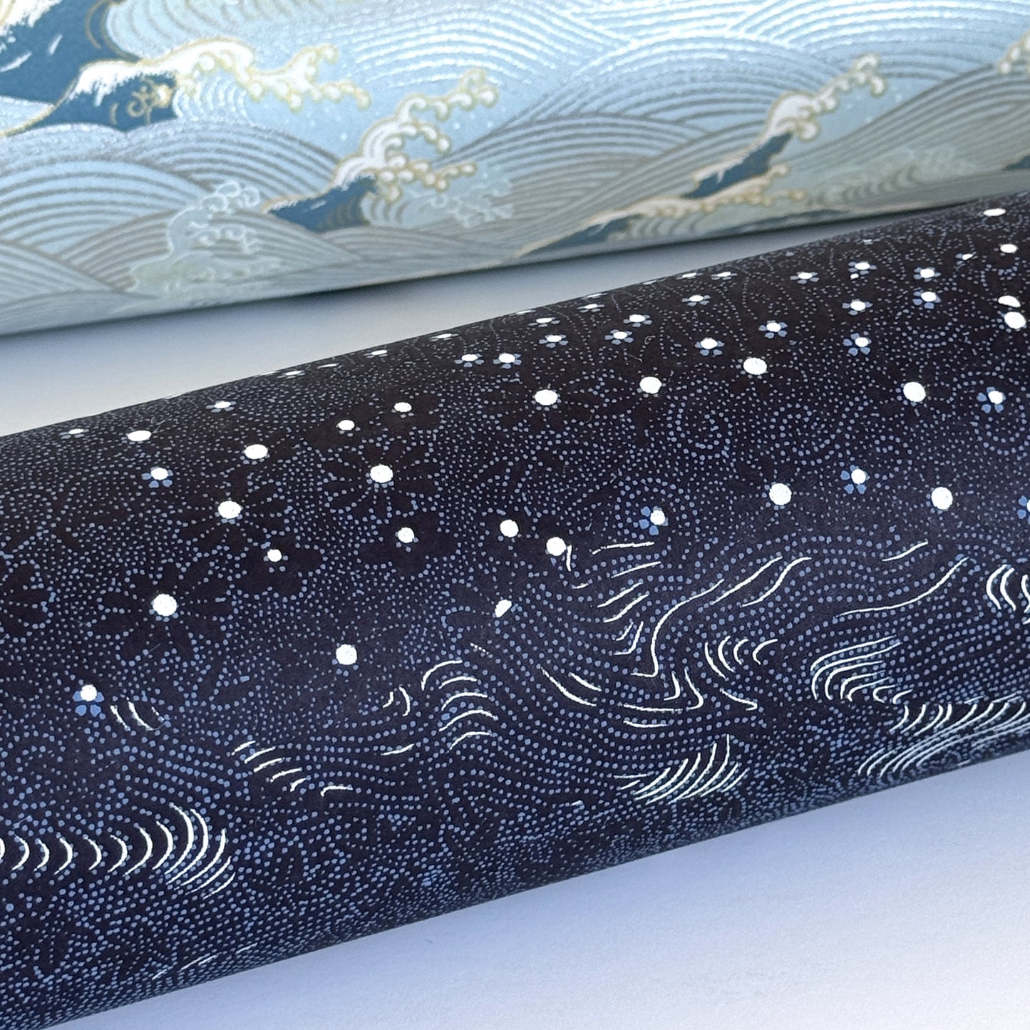 Japanese chiyogami paper. Inky blue with a subtle pattern of a riverbank of flowers. Close-up