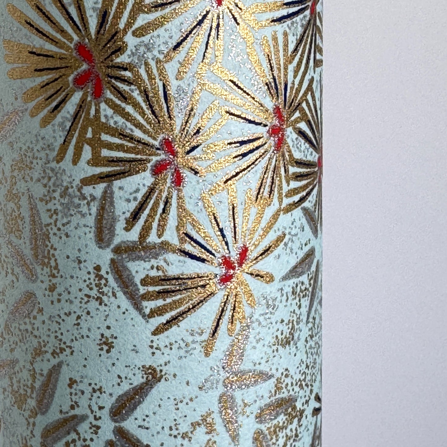 Japanese chiyogami paper silkscreen printed with gold pine needle design on a soft aqua backdrop. Close up