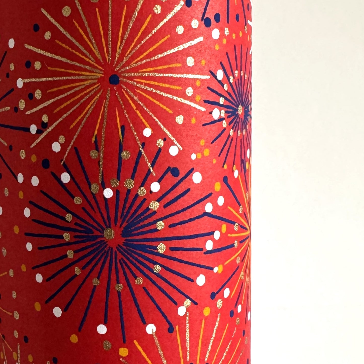 japanese chiyogami silkscreen printed paper with a pattern of fireworks in golds and purples on a red background. Close up