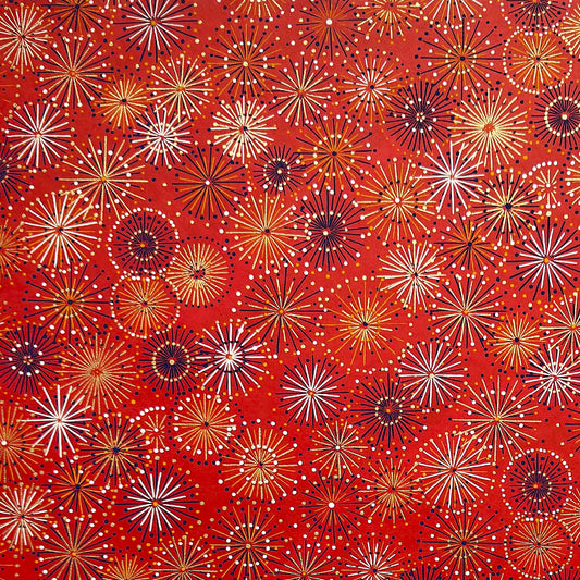 japanese chiyogami silkscreen printed paper with a pattern of fireworks in golds and purples on a red background.