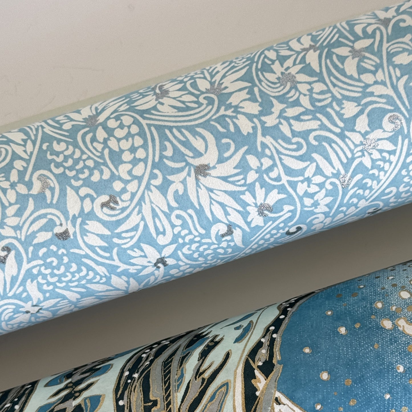 Japanese chiyogami paper - silkscreen printed - light blue backdrop with a small botanical pattern in white with silver accents. Close up