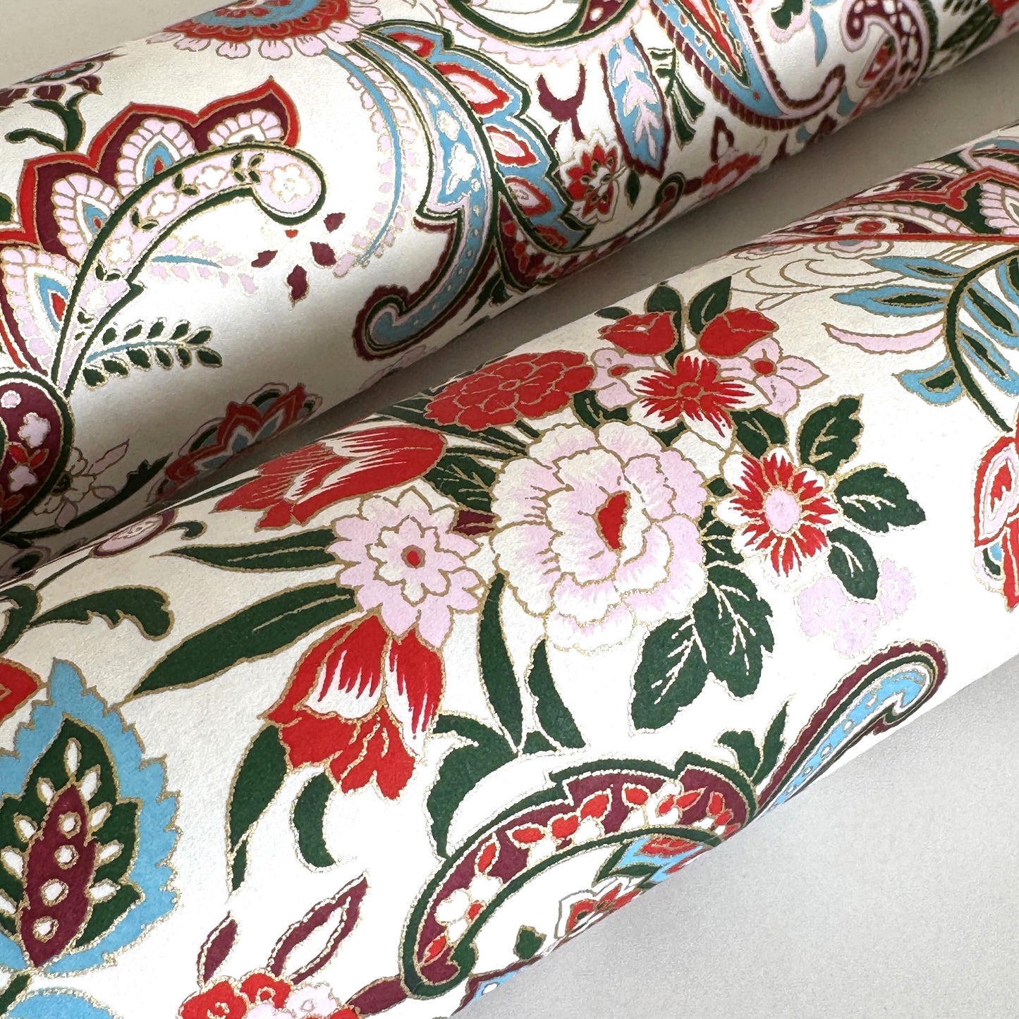 Japanese chiyogami paper silkscreened with a paisley floral style pattern in red, aqua, green and gold on a white background. Close-up of the flowers
