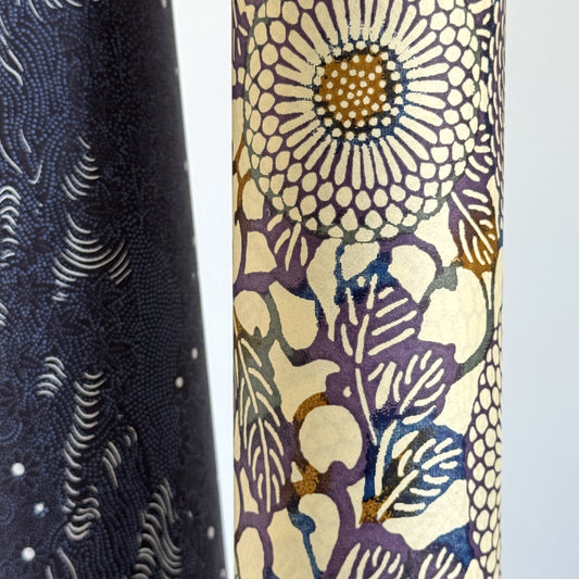 Japanese chiyogami silkscreen printed paper with a floral kiko pattern in purple and blue on a cream backdrop. Close up