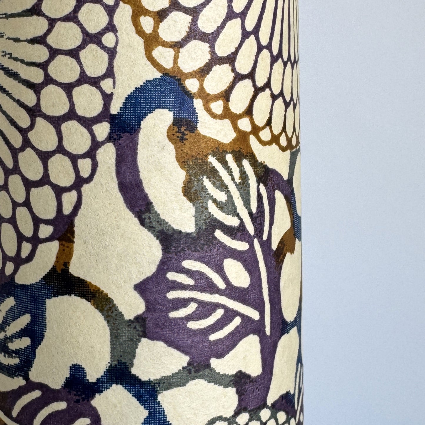 Japanese chiyogami silkscreen printed paper with a floral kiko pattern in purple and blue on a cream backdrop. Close-up