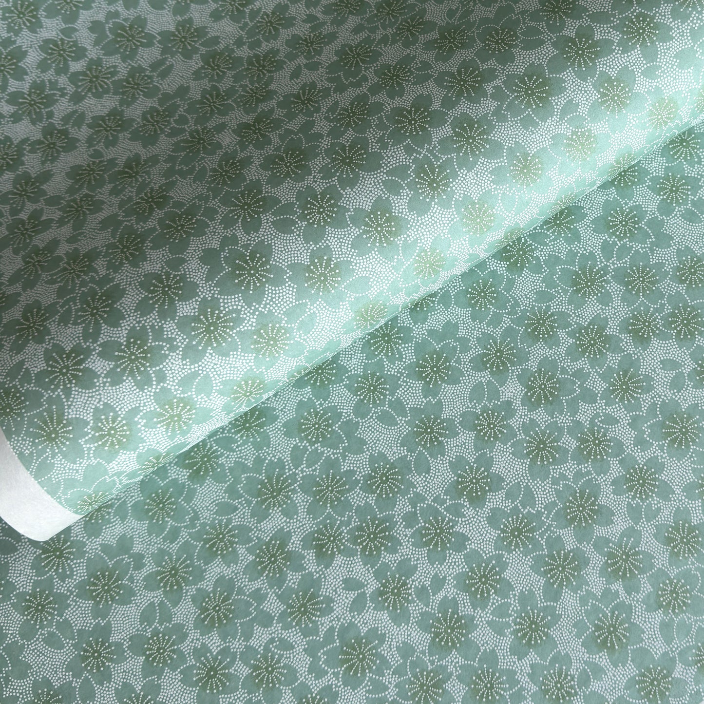 japanese silk-screen paper, chiyogami, with a cherry blossom flower repeat pattern in turquoise and white