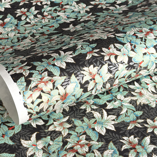 a sheet of Japanese chiyogami screen printed paper with a pattern of light green foliage on a black ground with silver botanical details