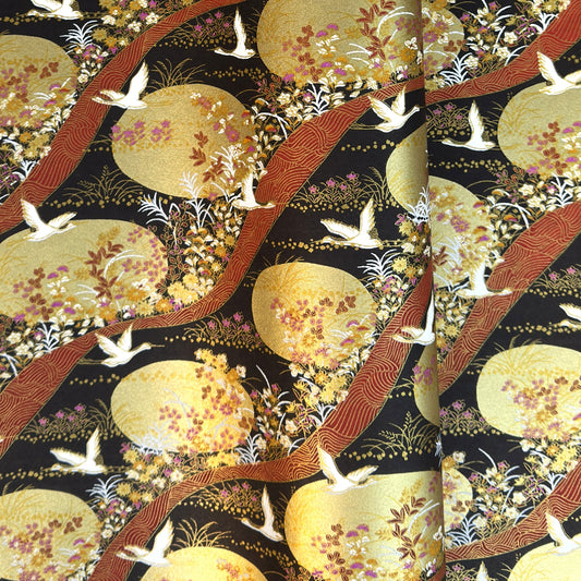 a sheet of Japanese yuzen chiyogami paper in white cranes, flowers and rivers in muted tones of autumn colours and lots of gold on a black ground.