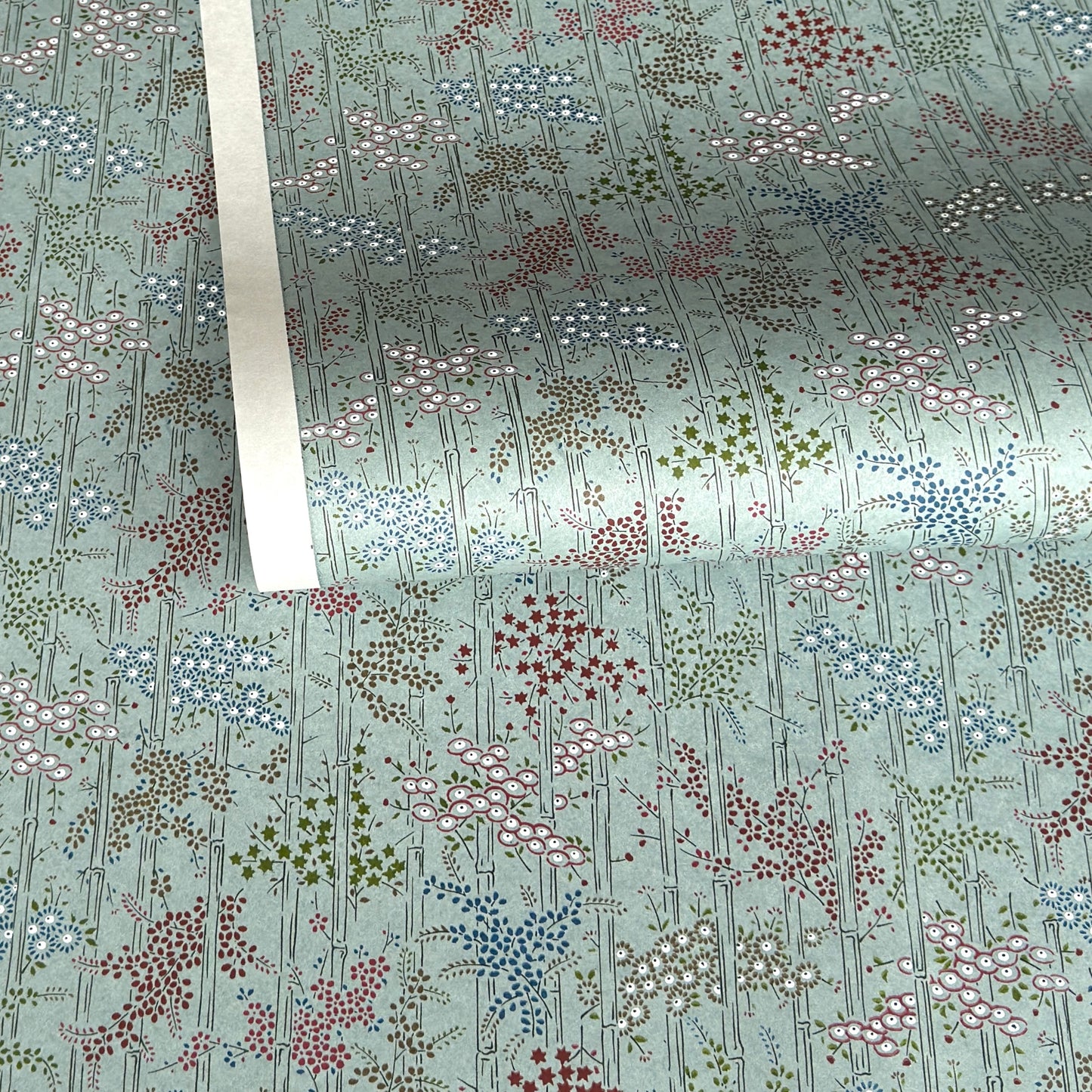 japanese silk-screen handmade paper showing pattern of bamboo, flowers and foliage on light teal backdrop