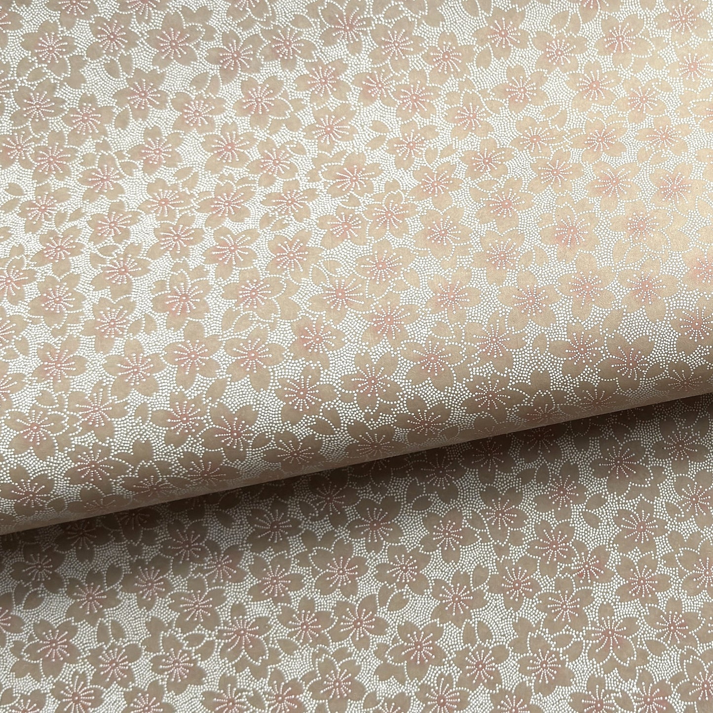 Japanese silkscreen chiyogami paper with a repeat pattern of cherry blossom flowers in taupe and white