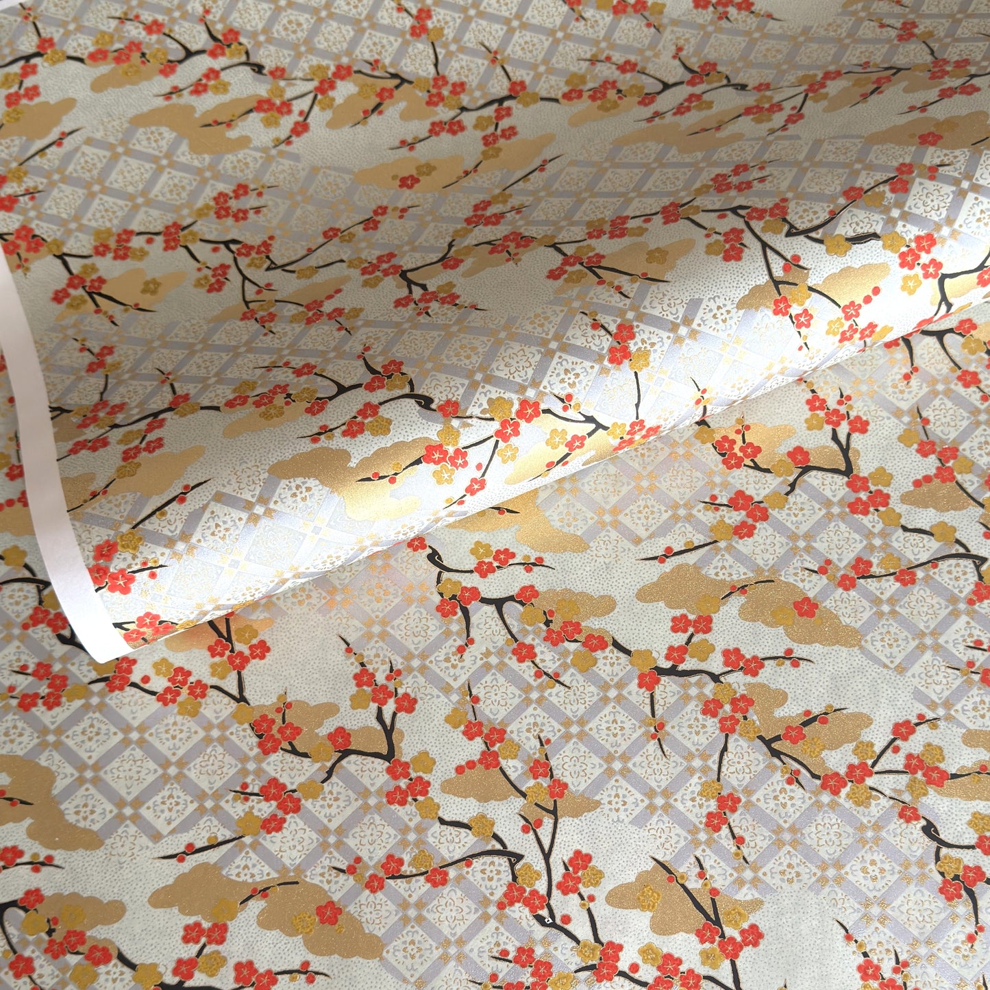japanese silk-screen handmade paper, chiyogami, showing branches of red cherry blossom and gold clouds on a backdrop of silver, cream and gold