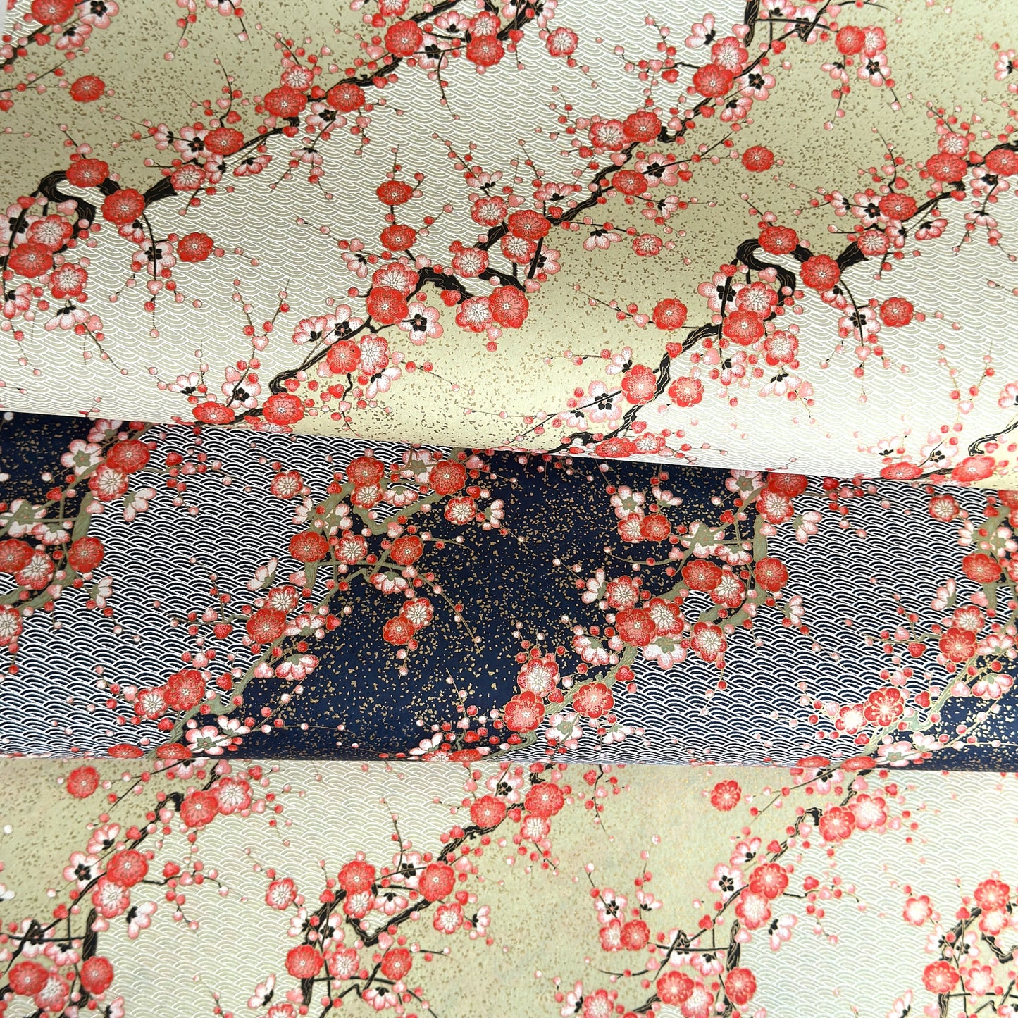 Japanese chiyogami silkscreen paper with diagonal branches of pink plum blossom on a sage green backdrop.