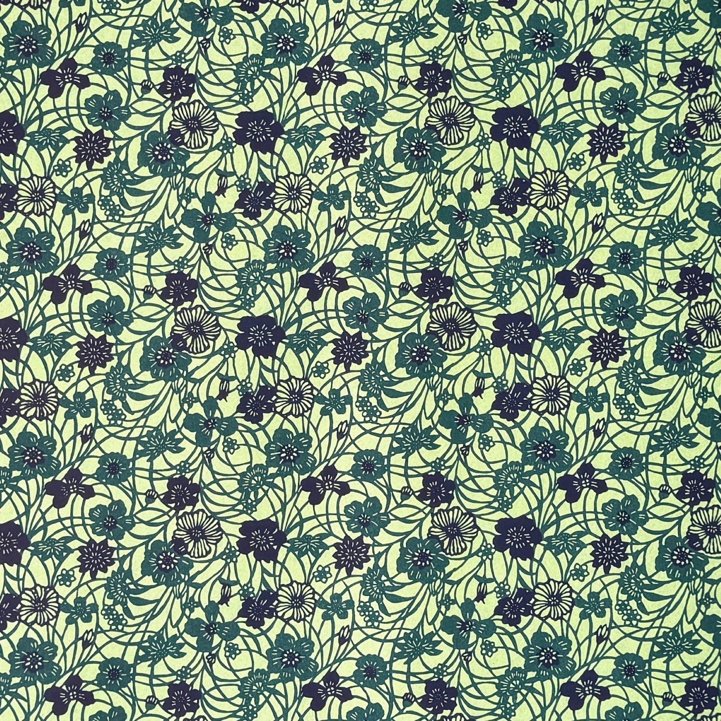a sheet of katazome paper with a floral design in shades of green and indigo blue.