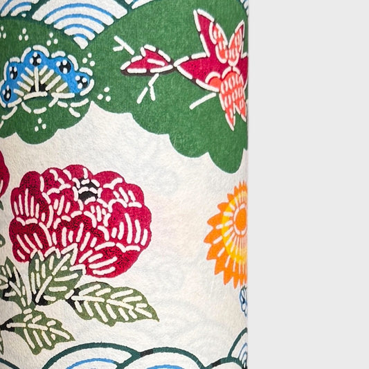 A colourful traditional pattern depicting stylised waves (seigaiha) with flowers and foliage in green, yellow, red and blue. A sheet of Japanese katazome paper.