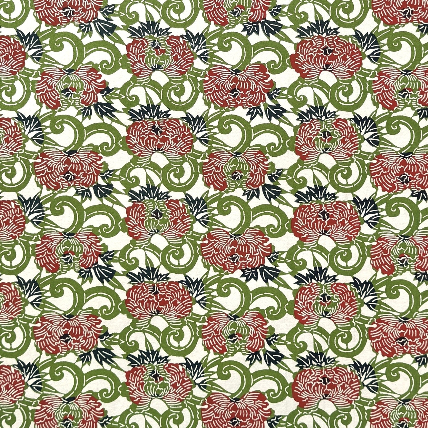 a sheet of katazome paper with a pattern of peonies (botan) in a rich red amongst green foliage