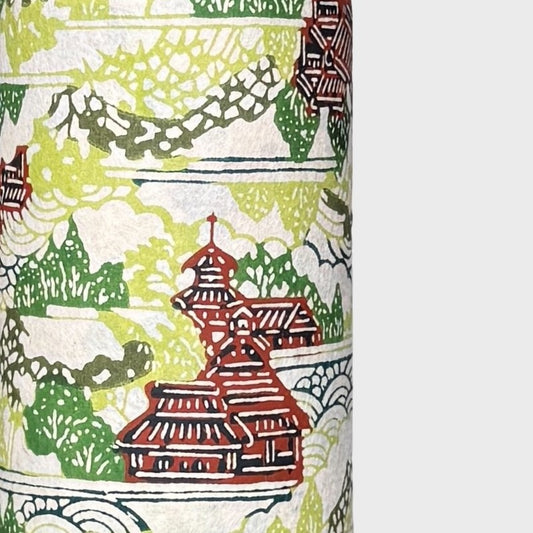 a sheet of katazome paper with a pattern of a hillside village in lime green, green and brown. Close up