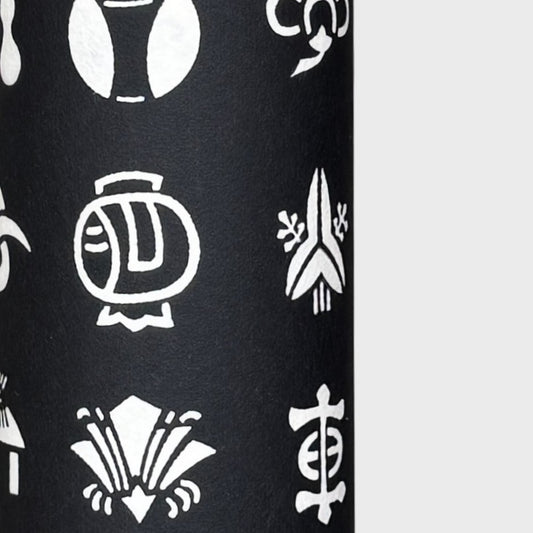 Japanese crests (mon) in monochrome. A sheet of stencil-dyed katazome paper in black with white crest symbols. Close up