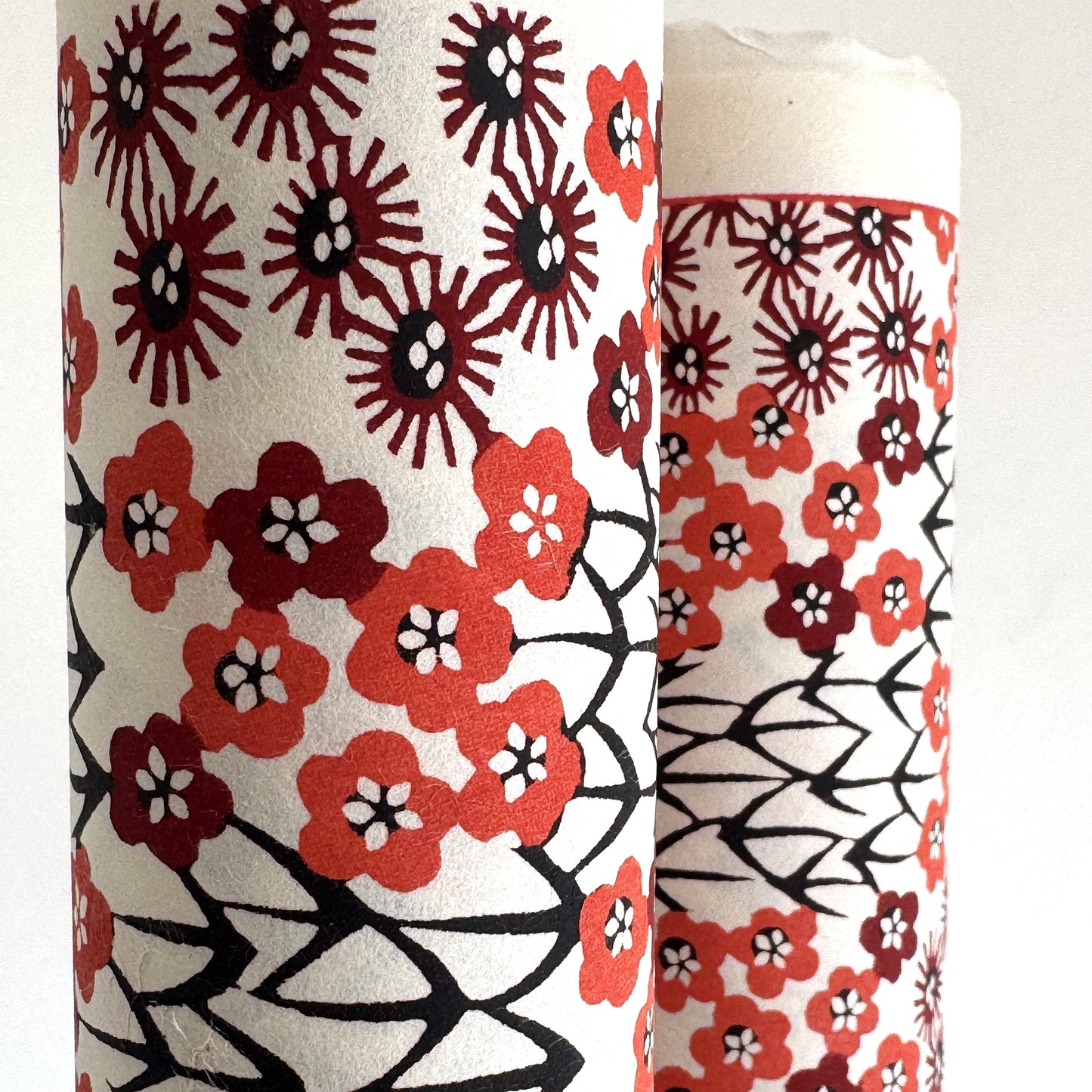 Japanese katazome-shi paper stencil -dyed with a small red flower design, little black stems on ivory paper. Close up